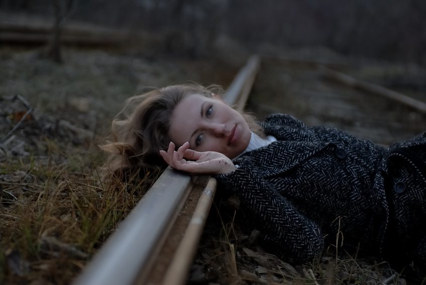 Woman laying hear on railroad track